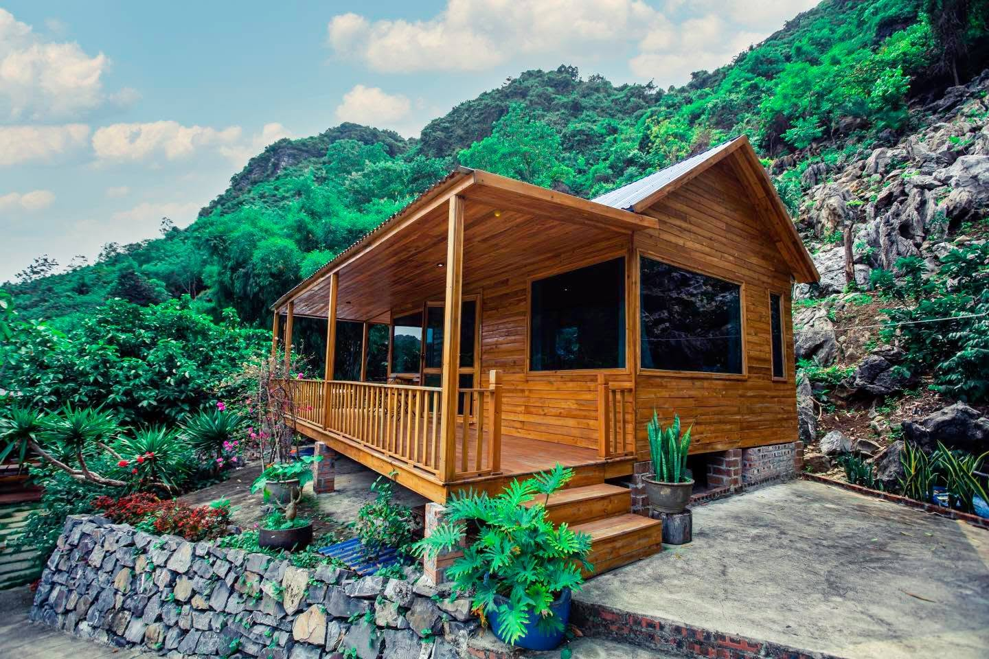 Little Cat Ba features rustic wooden houses surrounded by scenic mountains and a picturesque bay